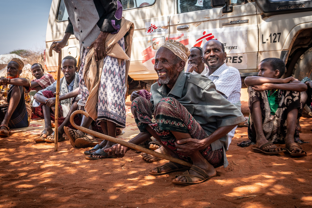 Waiting area for men in the shadow of a tree and an MSF car.